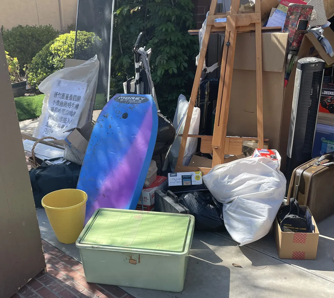 Household items and furniture stacked in a driveway during a garage cleanout